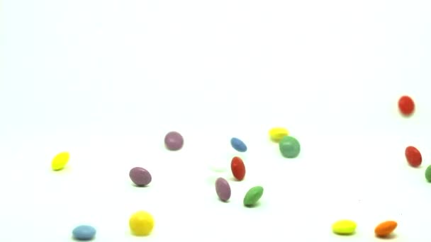 カラフルなボタン状のチョコレート チョコレートのドラッグ 色の錠剤が落ちます 白の背景 — ストック動画