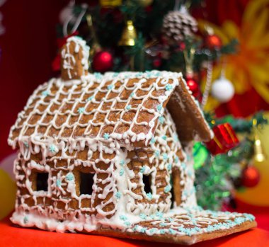 Noel ağacının arka planında zencefilli kurabiye evi