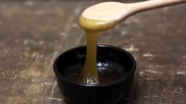 Bal, tahta kaşıktan kaseye damlıyor.
