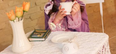 Küçük kız çay içiyor.