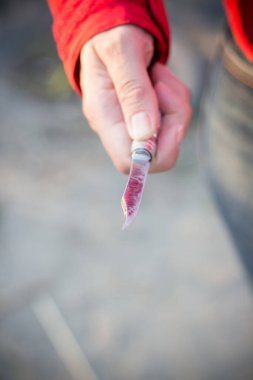 Bir katilin elinde tehlikeli bir bıçak var. Bıçakta kırmızı renk var.