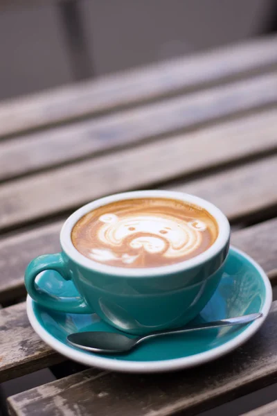 turquoise cup with coffee, painted bear, stands on a wooden table