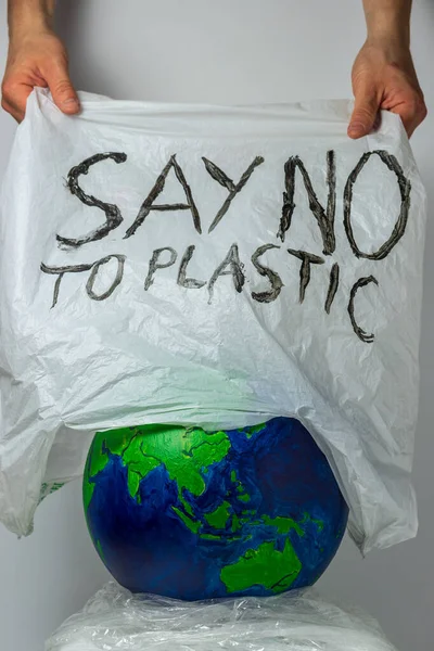 Nein zu Plastik. Menschliche Hände befreien den Planeten Erde von Plastiktüten. — Stockfoto
