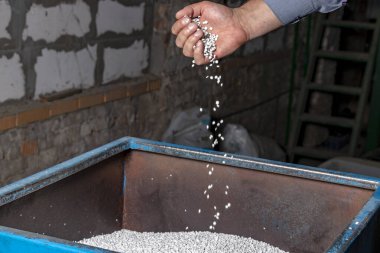White granules of recycled plastic trash in the hand clipart
