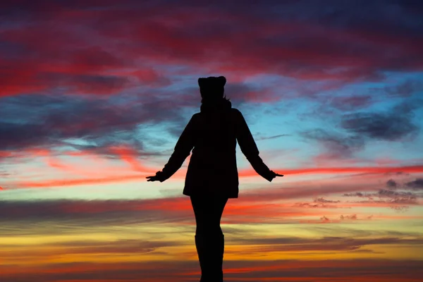 Silhueta de uma mulher com os braços abertos sobre o incrível céu do pôr do sol. Conceito de liberdade — Fotografia de Stock