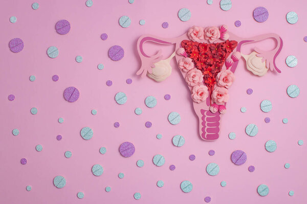 The concept of birth control - women's reproductive system, contraceptive pills, beautiful glamorous paper art on a pink background with glitter. Copy space for text