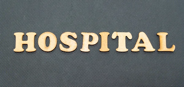 Hospital written on a black background with wooden lettering.