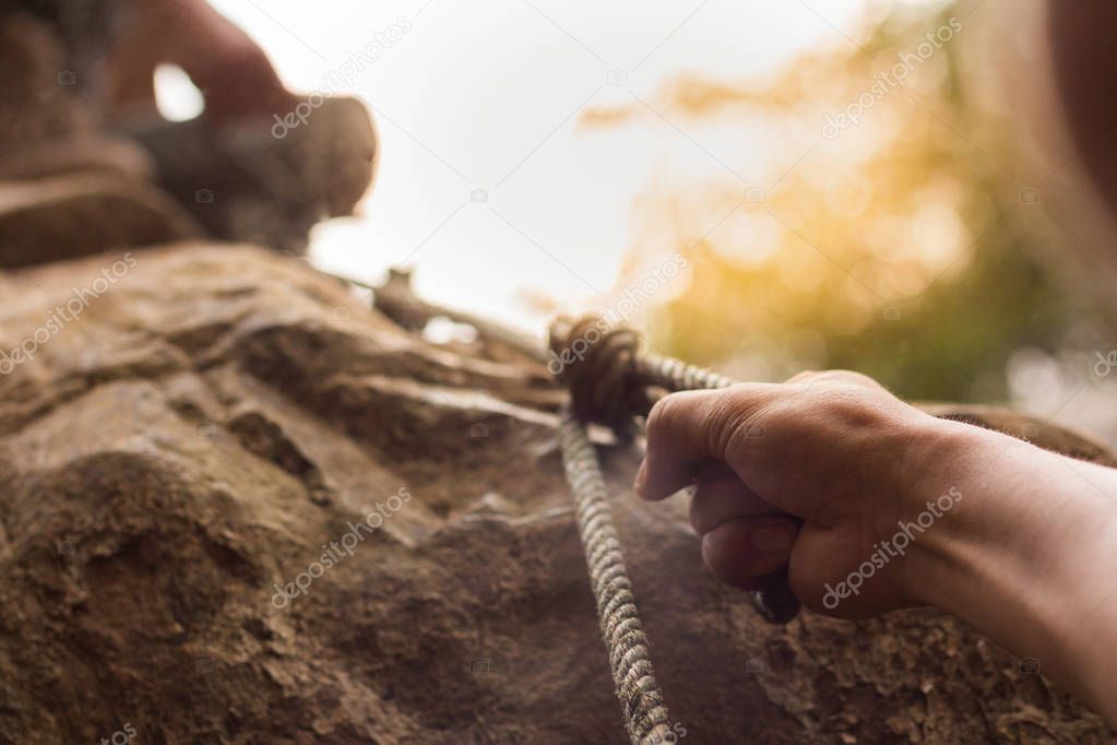 men climbing on rock outdoor, close-up image of climber hand 