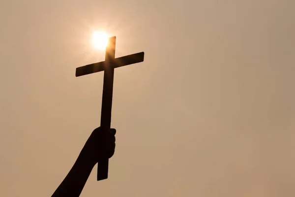 Ανθρώπινο χέρι κρατώντας ένα σταυρό, το φόντο είναι η Ανατολή του ηλίου., ΣΥΓΚ — Φωτογραφία Αρχείου