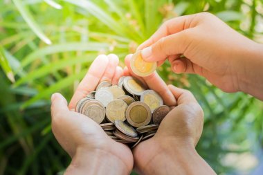 Ellerini, sikke eklemek madeni para küçük el doğa arka plan tarafından. 