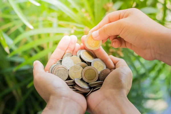 Ellerini, sikke eklemek madeni para küçük el doğa arka plan tarafından. 