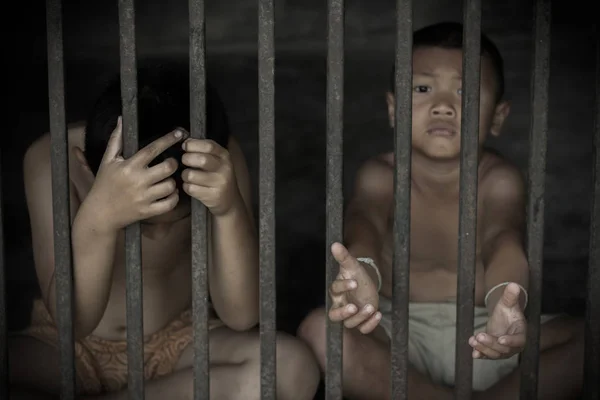Двое детей держат в клетке с грустными и безнадежными жертвами торговли людьми — стоковое фото
