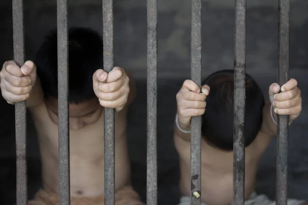 Двое детей сидят в клетке с грустными и безнадежными, жертвы торговли людьми, насилия в отношении детей — стоковое фото