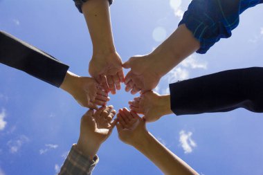 genç iş adamları koyarak onların el ele tutusun, gökyüzü arka plan, eller yığını. Birlik ve ekip çalışması kavramı.