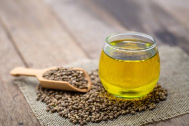  Tahta kaşıkta kenevir tohumu ve kahverengi kavanozda kenevir yağı.