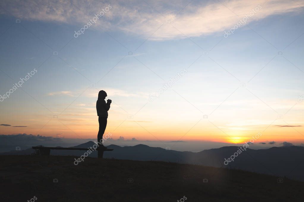 Silhouette of young  human hands  praying to god  at sunrise, Ch