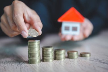 Yatırımcı göstermek el bir model ev ve sikke tutarak, tasarruf para 