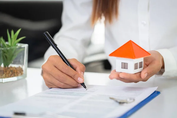 En kvinna undertecknar ett kontrakt för att köpa ett hem med en fastighet en — Stockfoto