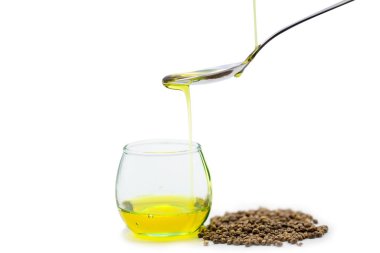 Kaşığa kenevir yağı, cam kavanoza kenevir yağı dökülüyor.