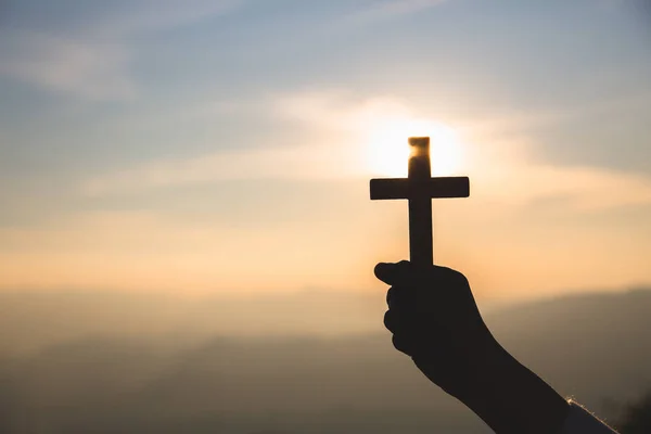 Silueta z rukou drží dřevěný kříž na pozadí sunrise — Stock fotografie