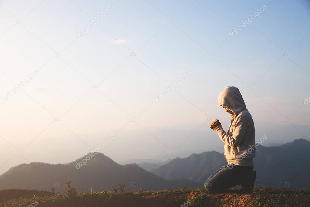 A women is praying to God on the mountain. Praying hands with fa