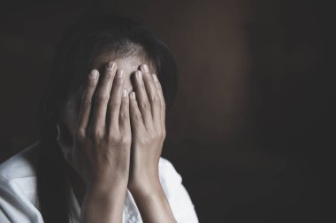 Genç bir kız karanlık odada oturuyor ve acı çekiyor..