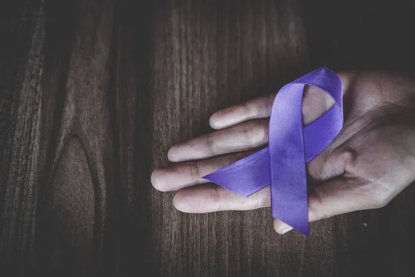 Purple ribbon in a woman\'s hand, Domestic Violence Awareness Mon