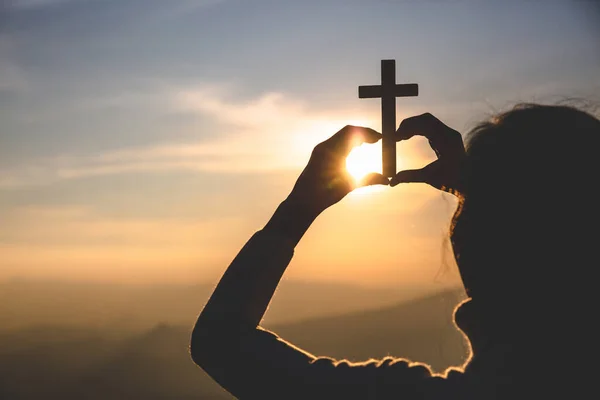 Religious concepts. Silhouette of a girl holding a crucifix to G — Stock Photo, Image