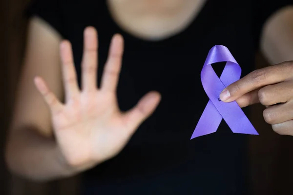 Purple ribbon in a woman\'s hand, Domestic Violence Awareness Month (October) concept with deep purple awareness ribbon.