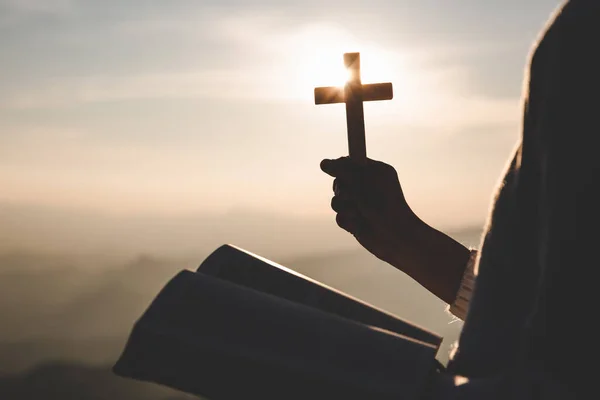聖書と十字架を持ちながら祈る女性のシルエット 朝に祈る 日の出の背景に手を携えて祈る女性 — ストック写真