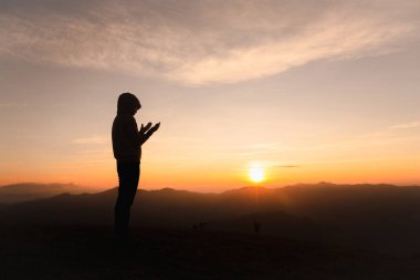 Gün batımında dua eden Hristiyan bir kadının silueti. Hıristiyan Dini kavramı geçmişi. Dua eden eller. Tanrı 'ya din kavramı ile tapmak.