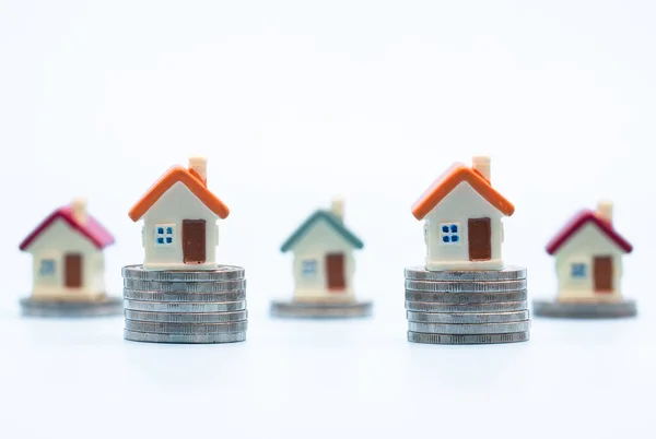 白を背景にコインのスタック上のミニハウス 投資不動産の概念 投資リスクと不確実性不動産住宅市場 — ストック写真