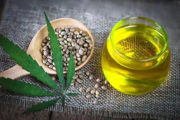 Hemp seeds and cbd hemp oil. Hemp seeds in wooden spoon and hemp essential oil in small glass bottle, medical marijuana concept.