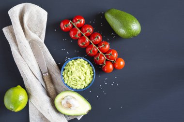 Geleneksel neşeli Meksika sosu guacamole seramik kase ve malzemelerin koyu arka plan üzerine. Üstten Görünüm. Düz yatıyordu. Kopya alanı.