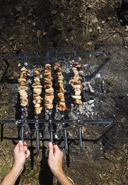 Iemands handen met sappig en lekker varkensvlees vlees kebab op spies. Grill buiten. Buiten BBQ-partij concept. Begin van de lente. Vlees achtergrond. Bovenaanzicht. — Stockfoto