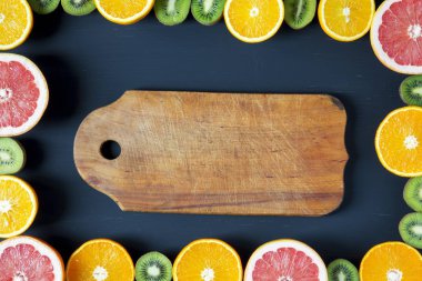 Düz yatıyordu. Üstten Görünüm. Dilimlenmiş renkli taze meyve ile Yönetim Kurulu: kivi, portakal, greyfurt ve mandarin siyah arka plan üzerine. Yaz arka plan.