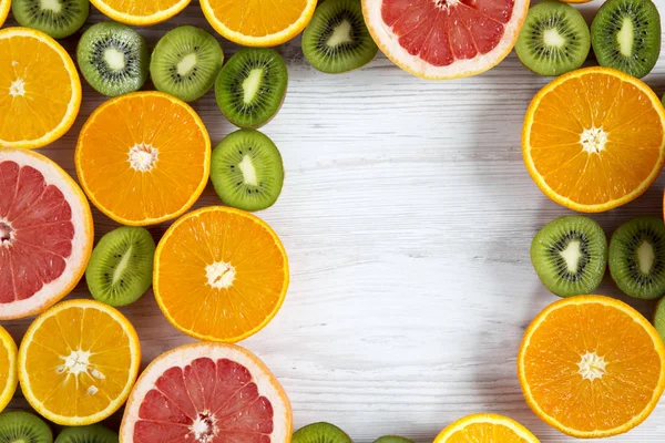 Deitado. Vista superior. Espaço de cópia com kiwi fatiado, laranja, toranja e tangerina no fundo de madeira leve. Fundo de verão — Fotografia de Stock