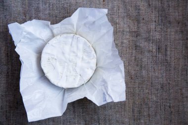 Yuvarlak peynir camembert veya kağıt brie. Metni kopyalayın. Düz yatıyordu. Üstten Görünüm. Yukarıdan. Eski çuval bezi doku.