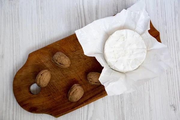 Sýr camembert nebo brie na tmavé dřevěné desce s oříšky. Lehké dřevěné pozadí. Produkce mléka. Byt leží. Z výše uvedeného. Pohled shora. — Stock fotografie