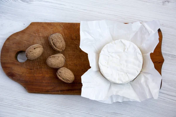 Queso camembert o brie sobre tabla de madera oscura con nueces. Fondo de madera claro. Producción de leche. Acostado. Desde arriba. Vista superior . —  Fotos de Stock