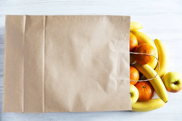 Saco de papel de frutas diferentes no fundo de madeira branco. Deitado. Vista superior . — Fotografia de Stock