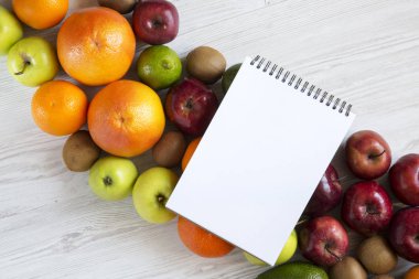 Not Defteri ile ham meyve Beyaz ahşap arka plan üzerinde ayarlayın. Sağlıklı gıda kavramı, üstten görünüm. Düz yatıyordu. Yaz arka plan.
