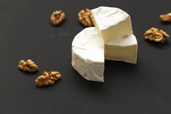 Camembert kaas of brie met walnoten op donkere achtergrond. De productie van de melk. Zijaanzicht. Close-up. Kopiëren van ruimte. — Stockfoto