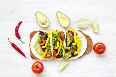 Ekmeği ile domuz eti, sebze, avokado, kireç. Beyaz ahşap arka plan. «Ana sayfa» görünümü, düz, ek yükü. 