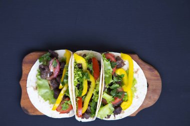 Et ve sebze siyah ahşap zemin, üstten görünüm panosunda ile tacos. Metin ve tasarım için siyah arka plan. Düz Üstten Görünüm.