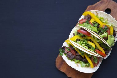 Et ve sebze siyah ahşap zemin, üstten görünüm panosunda ile tacos. Metin ve tasarım için siyah arka plan. Düz Üstten Görünüm.
