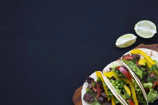 Los tacos callejeros mexicanos planos ponen composición con carne de res y verduras. Fondo oscuro. Copiar espacio. Vista superior plana . — Foto de Stock