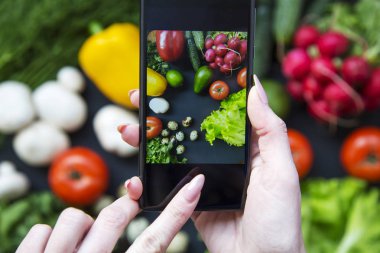 Kız alma resim onun smartphone ile sağlıklı yiyecek. Vegan gıda kavramı. Üstten Görünüm.