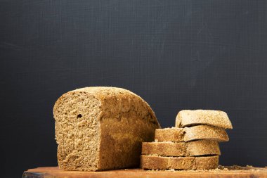 Ekmek ahşap tahta üzerinde dilimlenmiş. Koyu arka plan. Yan görünümü. Kopya alanı.