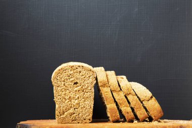 Ekmek ahşap tahta üzerinde dilimlenmiş. Koyu arka plan. Yan görünümü. Kopya alanı.